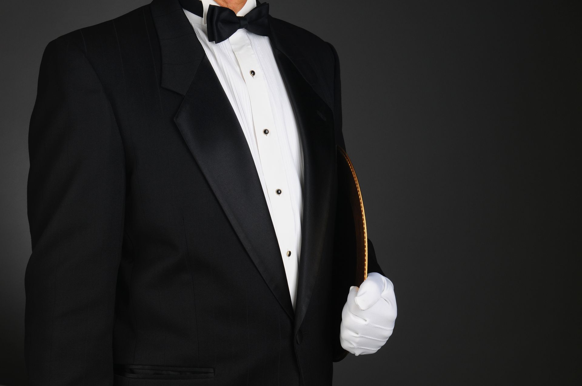 A concierge in formal attire holding a gilded service tray