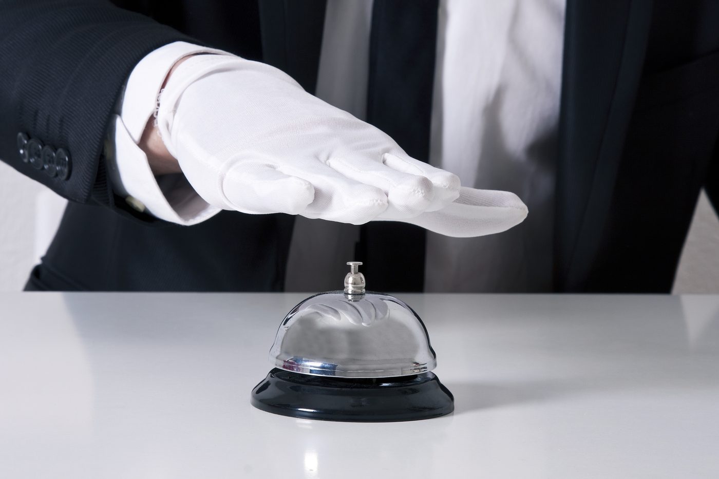 A white-gloved hand poised over a service bell